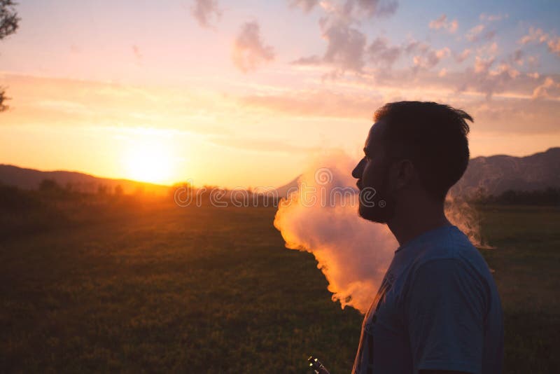 Man with Beard Smoke Electronic Cigarette Outdoor. Smoke of Electronic