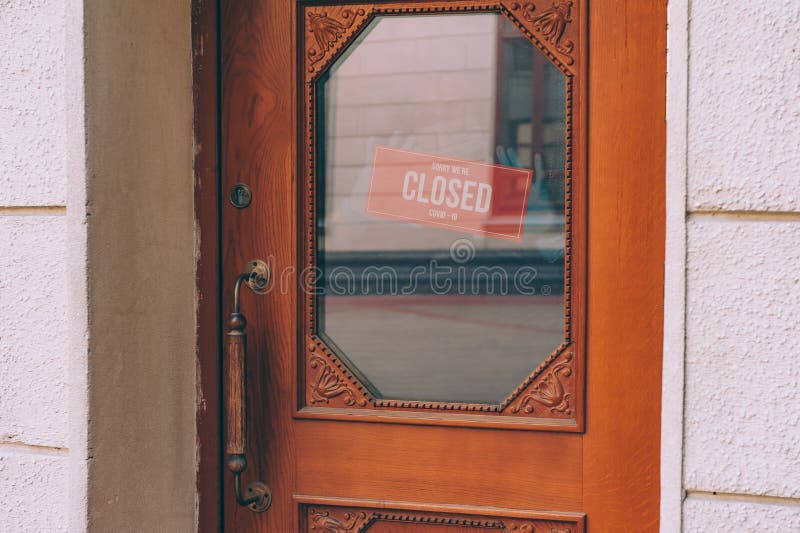 Man behind a glass door with a sign Sorry We`re Closed COVID-19.