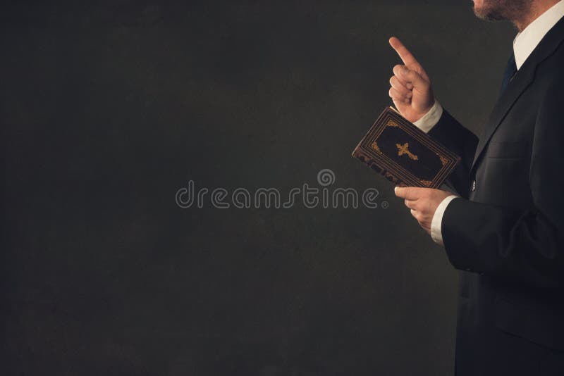 De pie hombre en un traje La biblia asentir dedo.