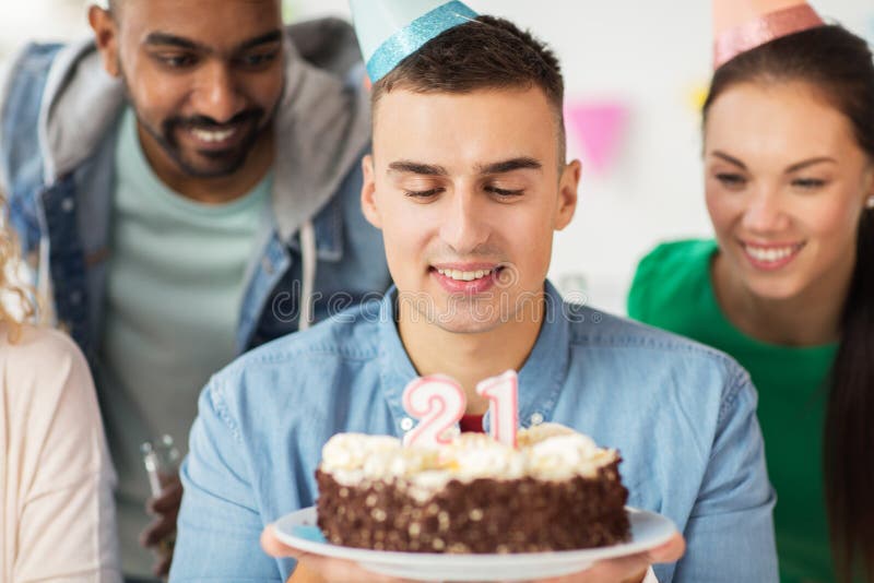 Man with birthday cake and team at office party