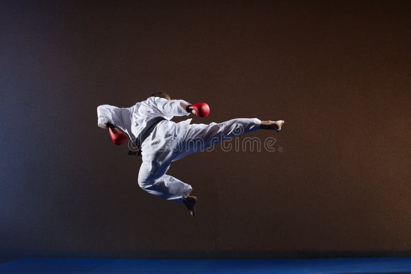 A man with a black belt beats a kick in a jump