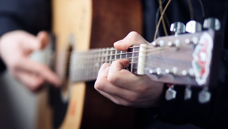 A man playing on a beautiful wooden acoustic guitar royalty free stock photo A man playing on a beautiful wooden acoustic guitar royalty free stock photo