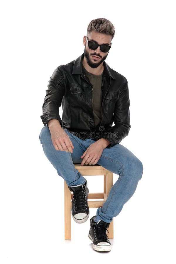 Man in Black Jacket and Blue Jeans with Arm on Knee Stock Image - Image ...