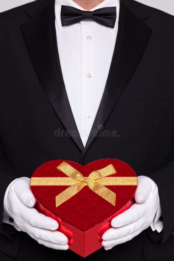 Man in black tie holding a heart shaped box of chocolates