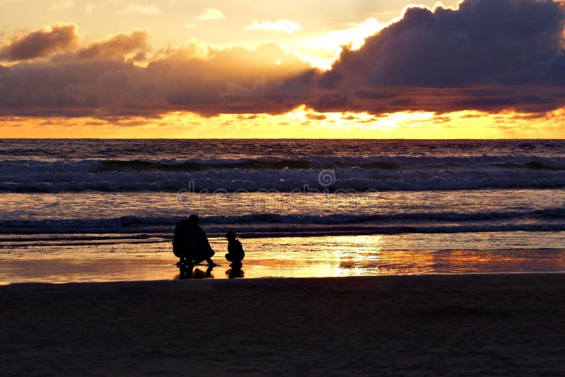 Man and boy on beach at sunset
