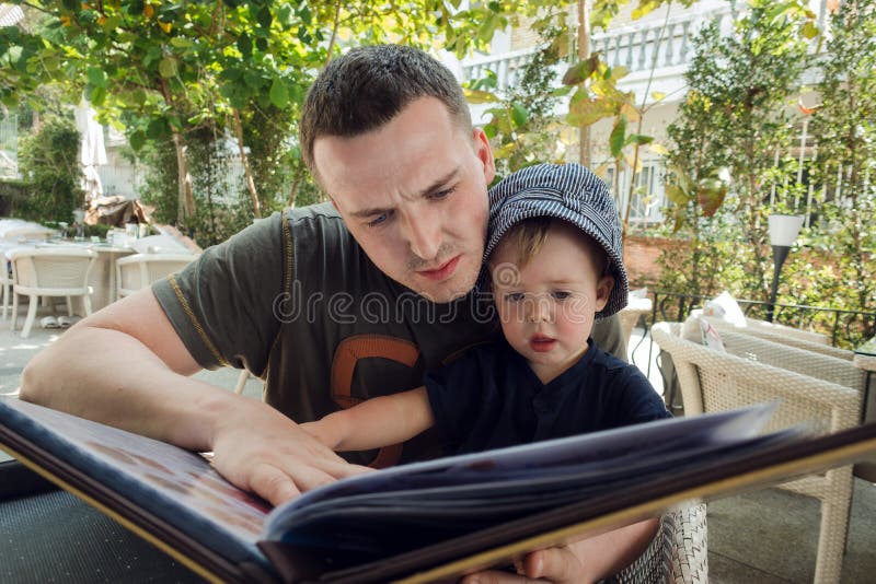 Man with boy exploring book on terrace royalty free stock images Man with boy exploring book on terrace royalty free stock images