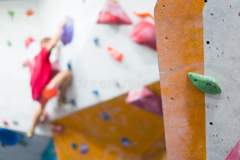 Man in Bright Clothes Climber on Artificial Climbing Wall in Gym Stock