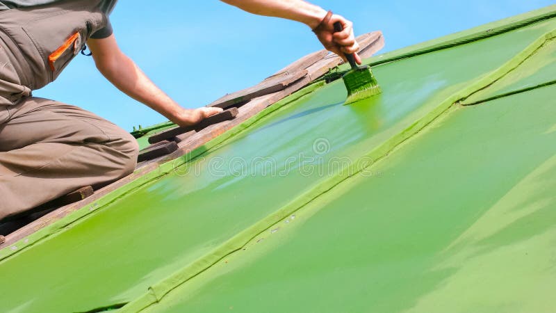 Man Brushing Green Paint onto the Roof stock photo Man Brushing Green Paint onto the Roof stock photo