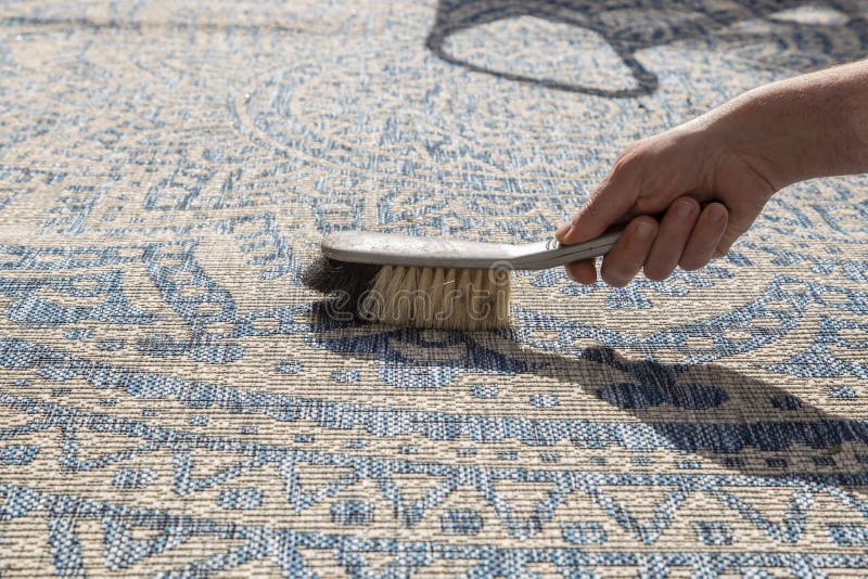 Man brushing an outdoor rug in a garden with a hand brush. stock photography Man brushing an outdoor rug in a garden with a hand brush. stock photography