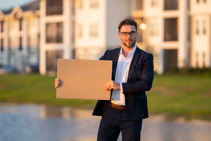 Man in business suit holds the sign, blank card. Placard ready for your product. Sign to your text. Business man showing royalty free stock photo