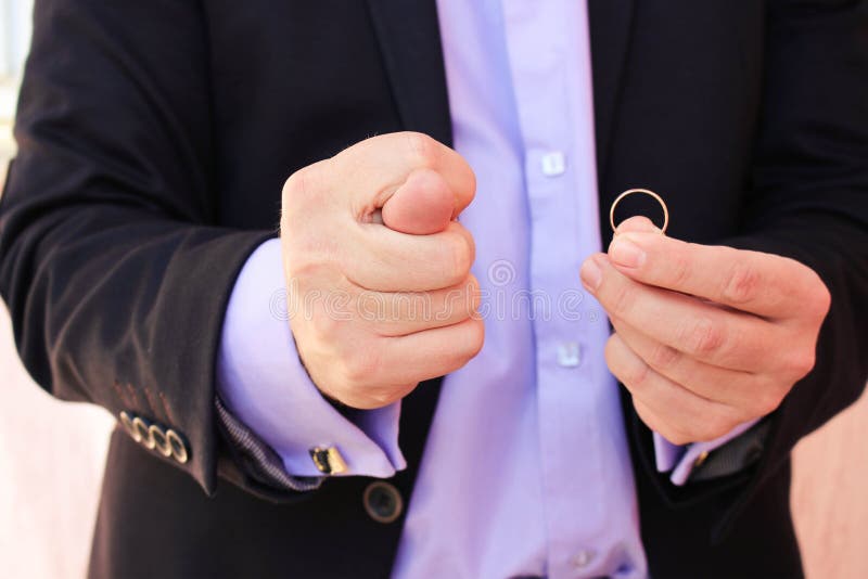 A man in a business suit shows figo, on the other hand shows a wedding ring. The concept of the man does not want to marry royalty free stock photography A man in a business suit shows figo, on the other hand shows a wedding ring. The concept of the man does not want to marry royalty free stock photography