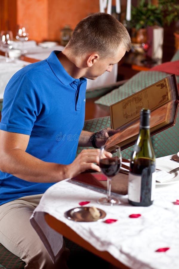 The man in cafe and chooses meal under the menu