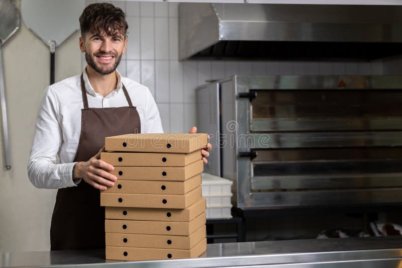 Man cafe worker holding cardboard stack of pizza boxes stock photo