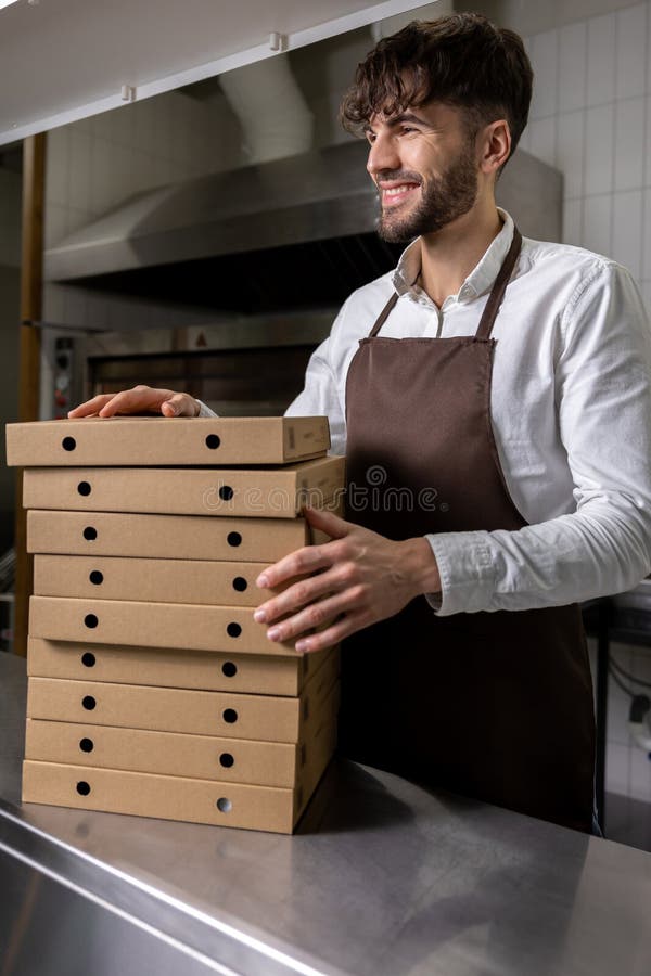 Man cafe worker holding cardboard stack of pizza boxes stock image