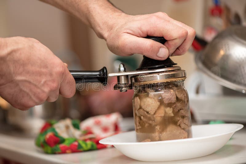 Man is canning pork stew, process close-up. Homemade cooking with a traditional recipe, Ukrainian cuisine royalty free stock photos Man is canning pork stew, process close-up. Homemade cooking with a traditional recipe, Ukrainian cuisine royalty free stock photos
