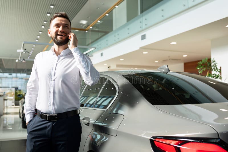 A Man in a Car Dealership Talking on the Phone Well Stock Photo Image
