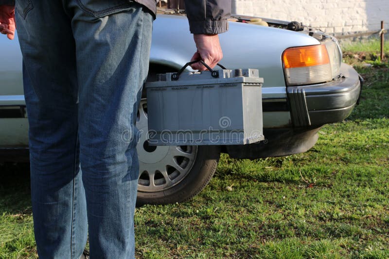 A Man Carries a Car Battery. Stock Photo Image of maintenance