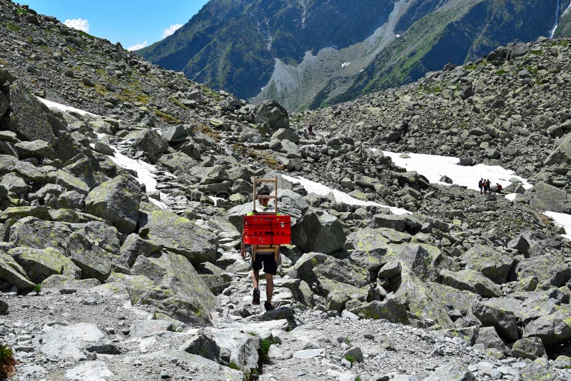 Muž nesie krabice z horskej chaty pod Rysmi pri Rysoch, Vysoké Tatry, Slovensko