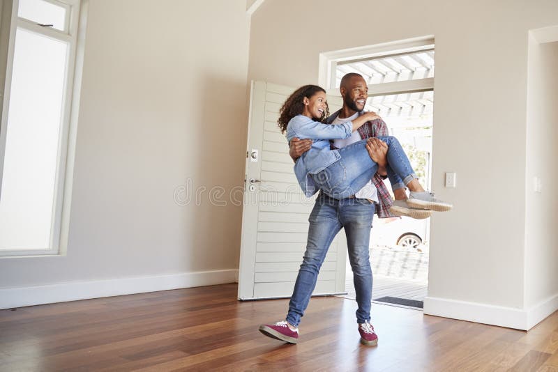 Man Carrying Woman Over Threshold Of Doorway In New Home