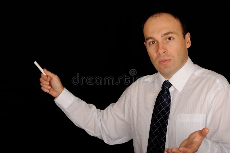 A view of a man holding chalk at a black chalkboard while teaching. A view of a man holding chalk at a black chalkboard while teaching.