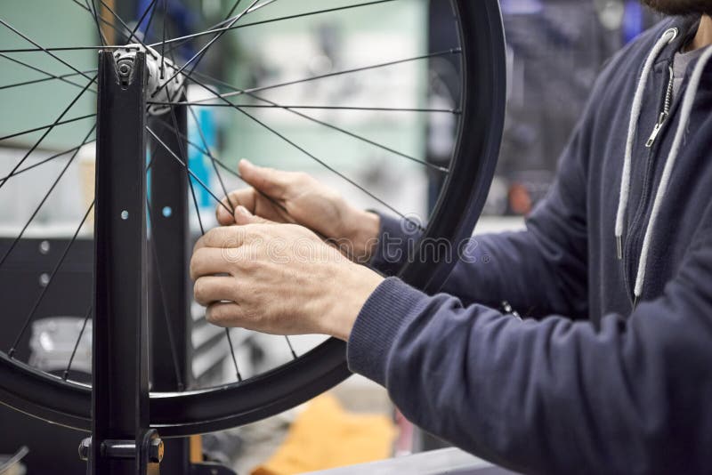 Man Checking the Tension of the Spokes of a Bicycle Wheel in His Bike
