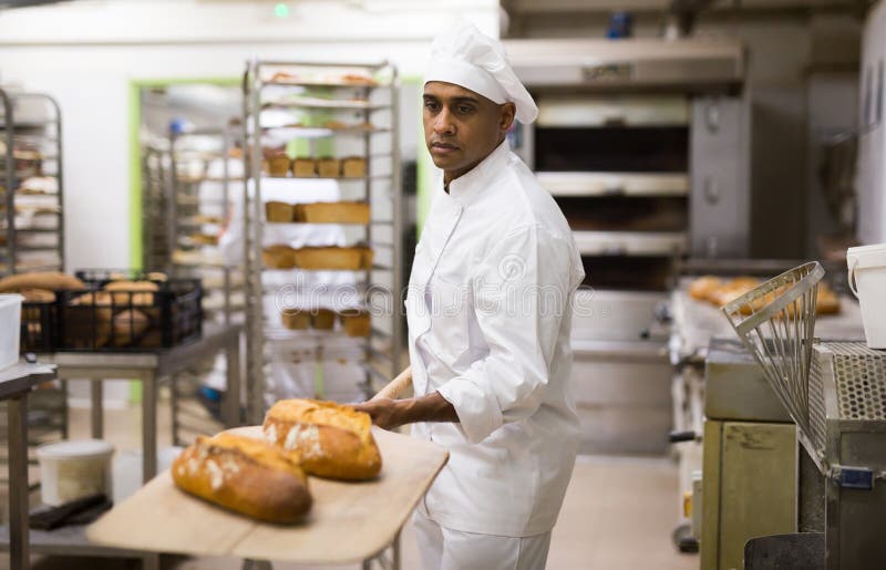 Man in Chefs Uniform with Bread on Shovel in Bakery Stock Photo Image