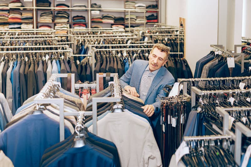 Man Select Clothes in a Boutique. Female Seller Stylist Helps To Choose ...