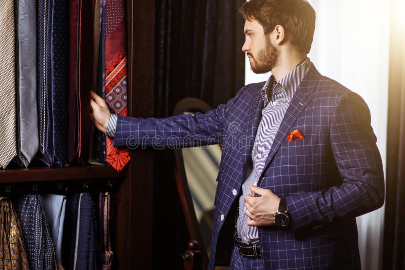 Man choosing necktie to match his suit in custome made garment fashion boutique stock image Man choosing necktie to match his suit in custome made garment fashion boutique stock image