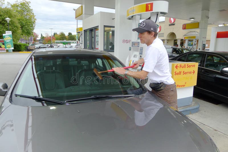 Man Cleaning the Car Windshield at a Gas Station Editorial Photography