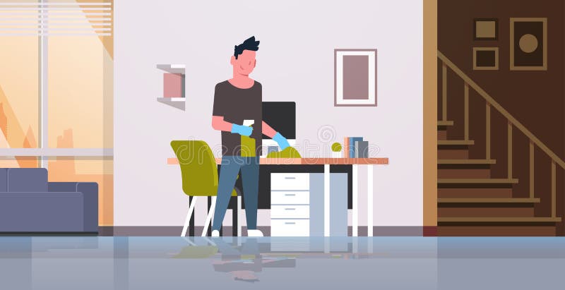 Man cleaning computer table with duster guy wiping workplace desk housework concept modern living room interior male