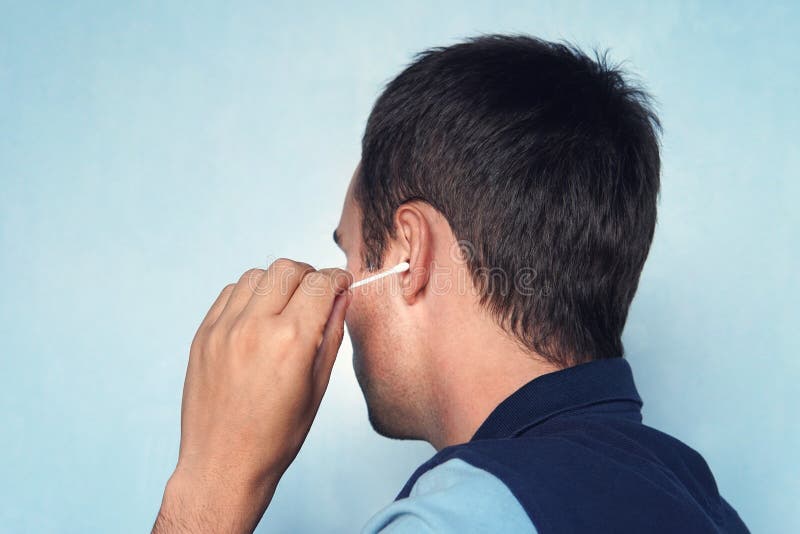 Man Cleaning Ear with Cotton Bud on Blue Background. Stock Image