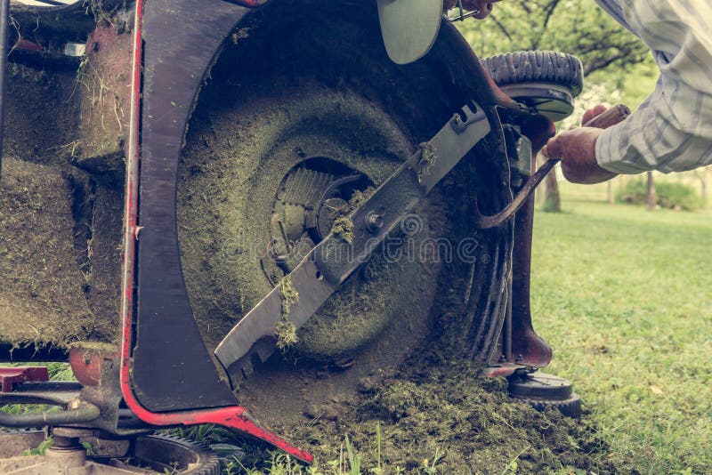 Man cleaning lawn mower blade.