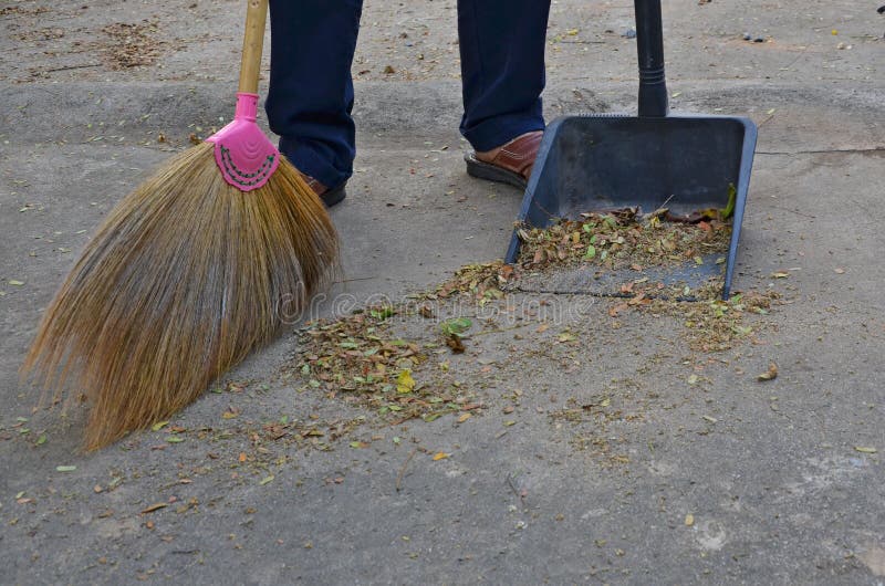 Cleaning concrete floor with grass broom and black plastic dustpan royalty free stock images Cleaning concrete floor with grass broom and black plastic dustpan royalty free stock images