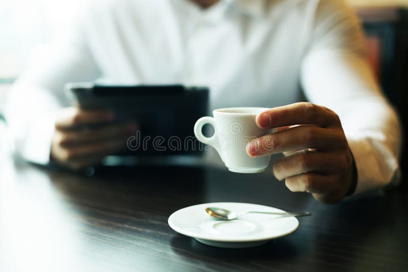 Man with coffee cup and tablet computer reading news at motning