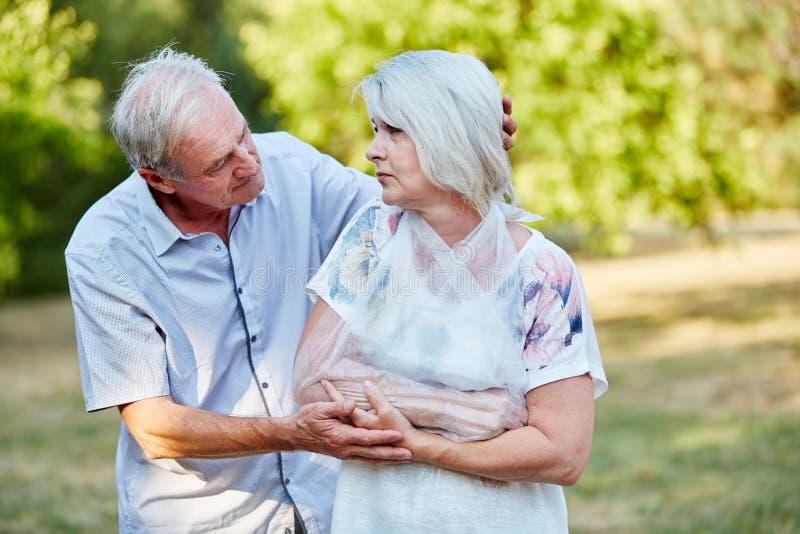 Man comforting old women with broken arm in a loop. Man comforting old women with broken arm in a loop