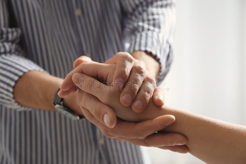 Man comforting woman on light background, closeup of hands. Help and support concept