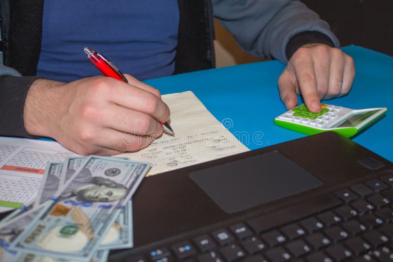 Man and Computer are Using a Calculator on the Table in the Office Room