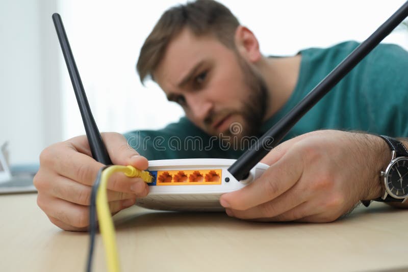 Man connecting cable to router at table, focus on hand. Wireless internet communication royalty free stock photo