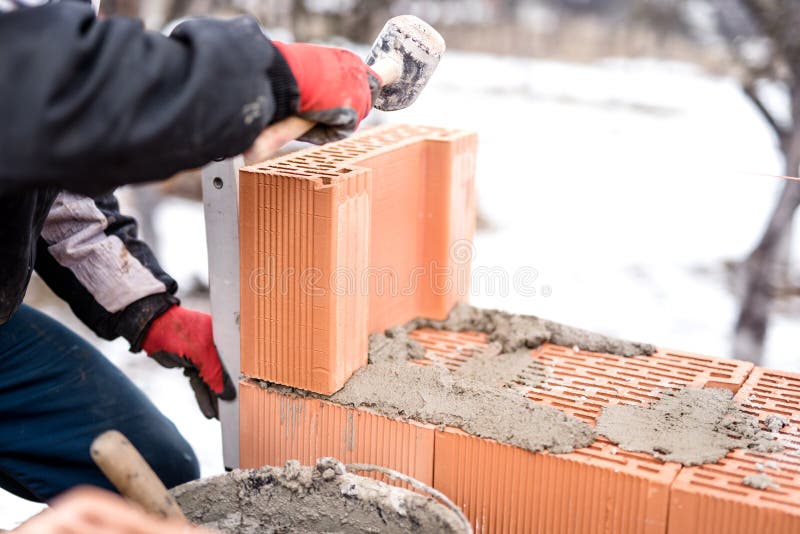 Man on Construction Site Working with Bricks and Mortar, Building House