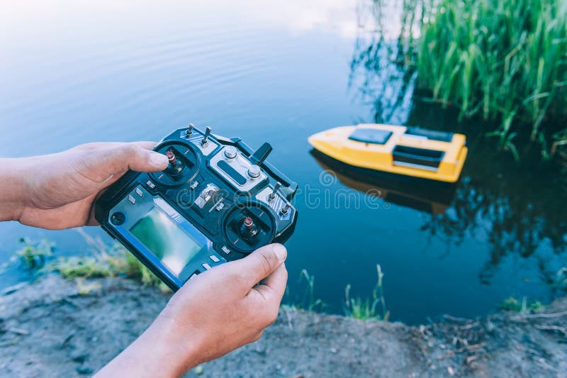 Man controls a remote control, a boat to bait fish in the lake