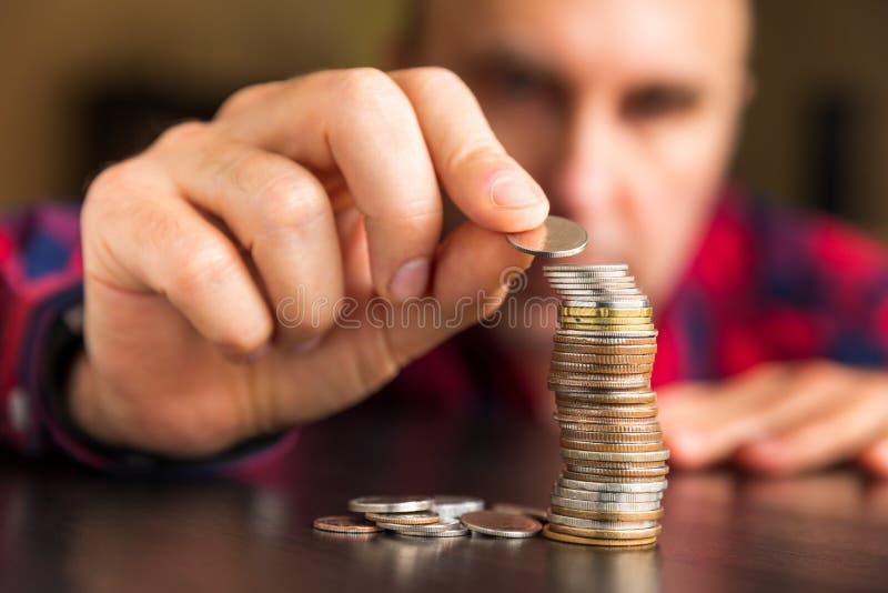 Man counts his coins on a table stock photo Man counts his coins on a table stock photo