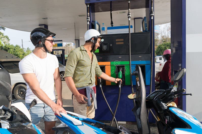 Man Couple On Gas Station Fuel Motor Bike, Happy Smiling Guys Travelling stock photo Man Couple On Gas Station Fuel Motor Bike, Happy Smiling Guys Travelling stock photo