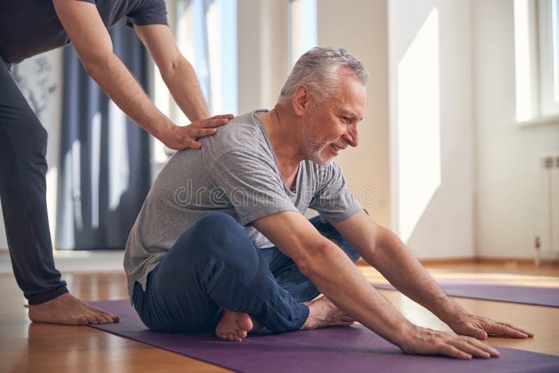 Smiling male performing a basic seated yoga exercise stock photography