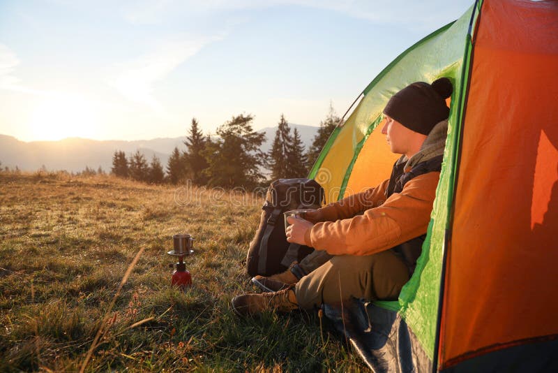 Man with Cup of Hot Drink in Camping Tent. Space for Text Stock Image