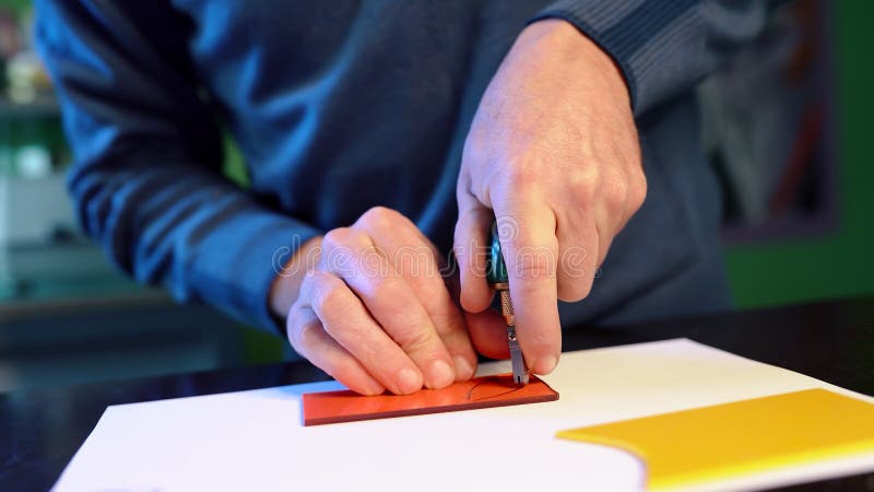 Man cuts with glass cutter details of future mural or stained glass window. Craftsman works with colored glass in fusing