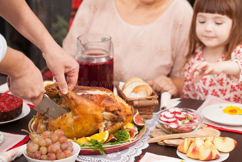 A man cuts off a piece of roast Turkey at the table stock photo A man cuts off a piece of roast Turkey at the table stock photo