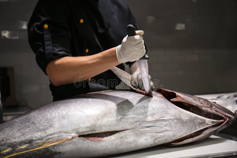 Man cutting fresh tuna on table in fish market