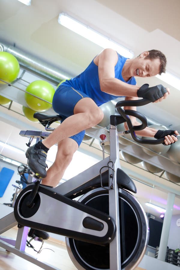 Cycling fit man on spinning bike in gym. Cycling fit man on spinning bike in gym