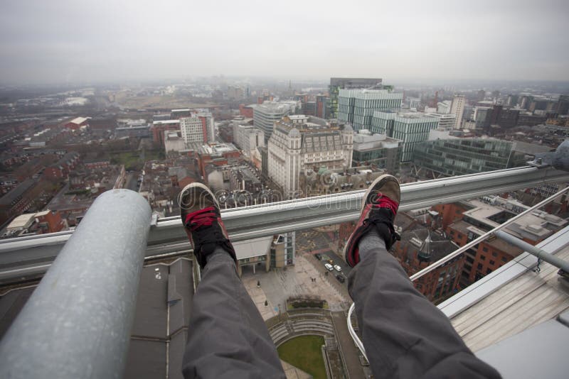 Man dangling feet over city view stock image Man dangling feet over city view stock image