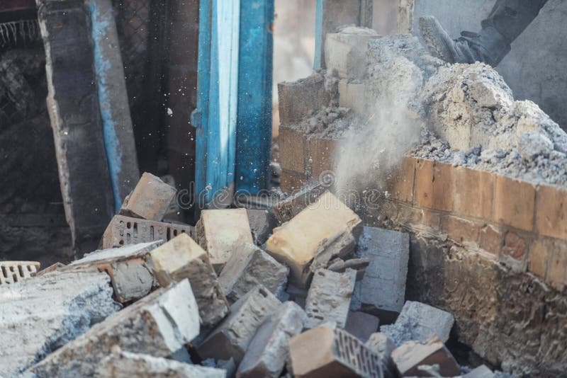 A Man Destroys a Wall of Old House. Dust and Bricks in Action Stock